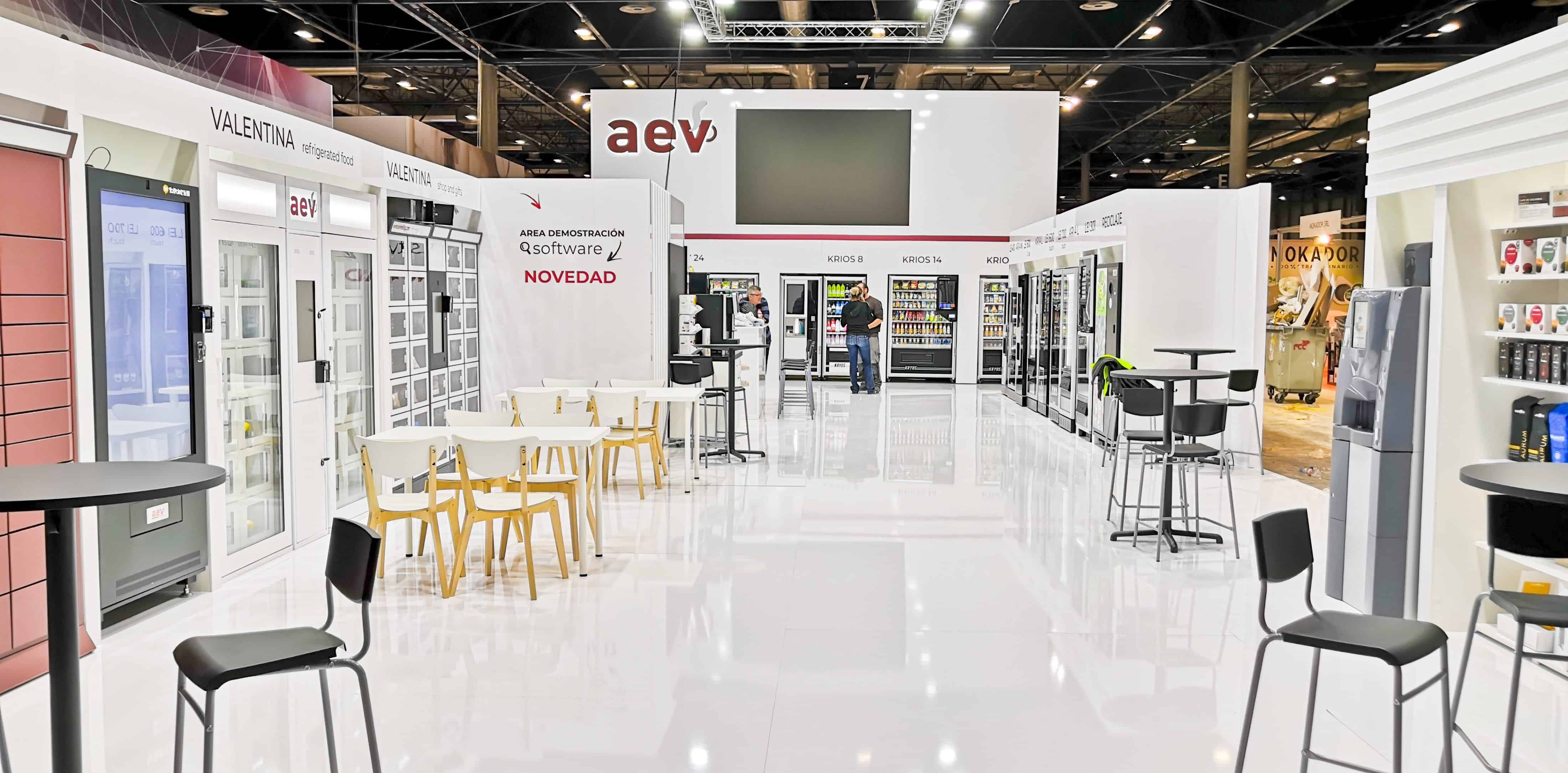 Stand con máquinas expendedoras, mesas de conversación y una zona central de circulación