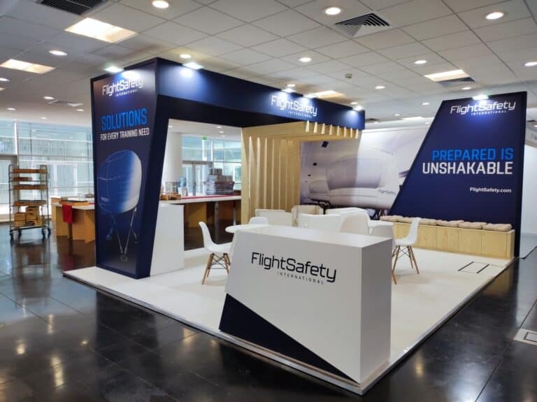 FlightSafety International aviation training booth with navy blue branding and wooden slat wall at a European trade show