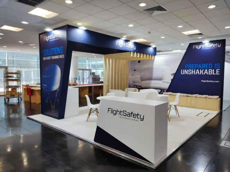 FlightSafety International aviation training booth with navy blue branding and wooden slat wall at a European trade show
