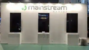 Custom ICE Barcelona exhibition stand for Mainstream Gaming built by Adam Expo Stand featuring illuminated branding wall and integrated display screens.